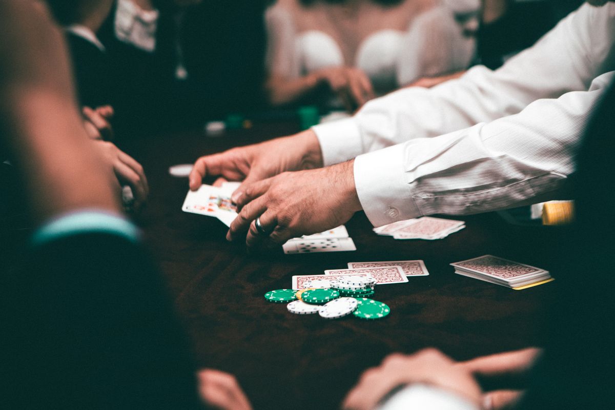 Pemain terkonsentrasi di meja poker dengan tumpukan kartu dan chip